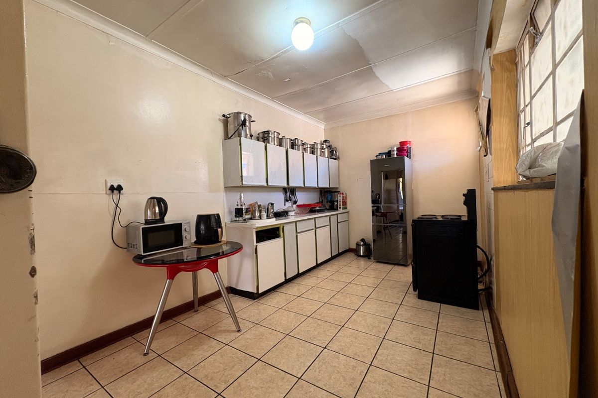 A functional kitchen featuring tiled flooring, built-in cabinetry, and a freestanding stove, requiring cosmetic updates to improve its overall condition and aesthetic appeal.