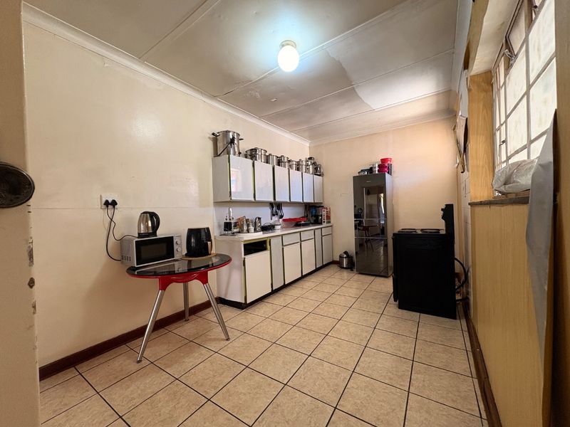 A functional kitchen featuring tiled flooring, built-in cabinetry, and a freestanding stove, requiring cosmetic updates to improve its overall condition and aesthetic appeal.