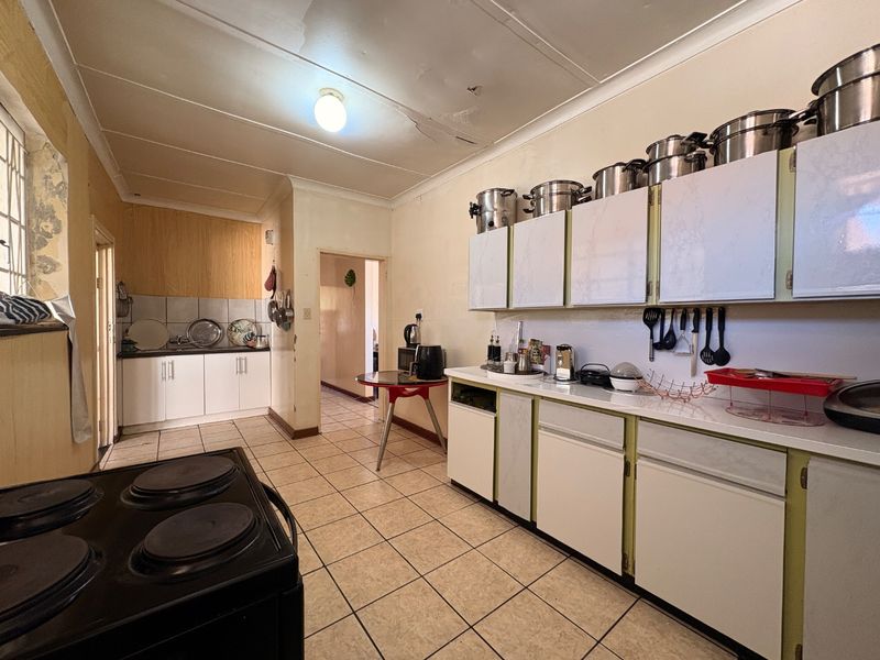 A dated kitchen featuring tiled flooring, built-in cabinetry, and a tiled backsplash, currently showing signs of wear and requiring cosmetic updates.