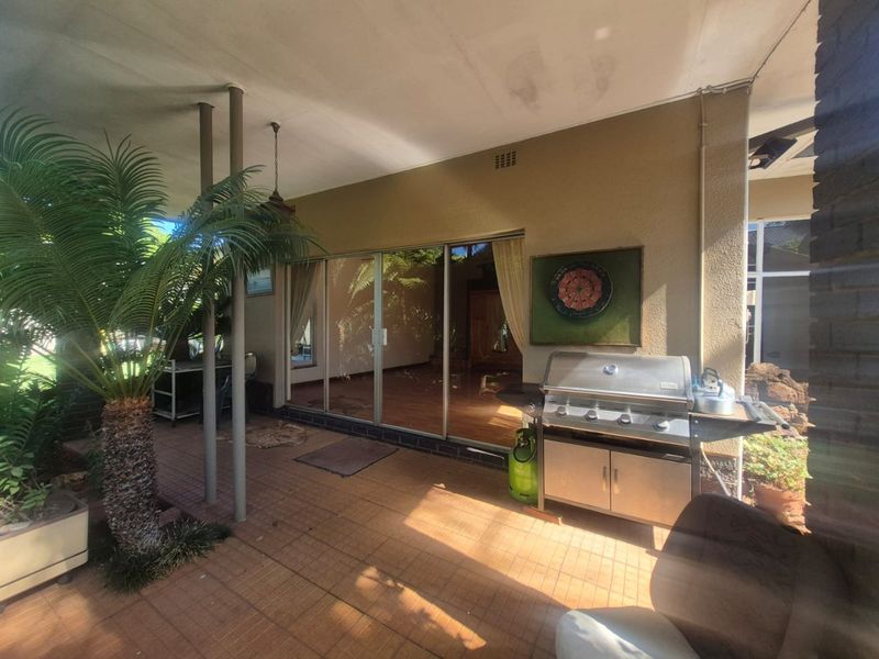 A covered patio area featuring tiled flooring and large sliding glass doors, providing a functional outdoor space for relaxation and entertainment.