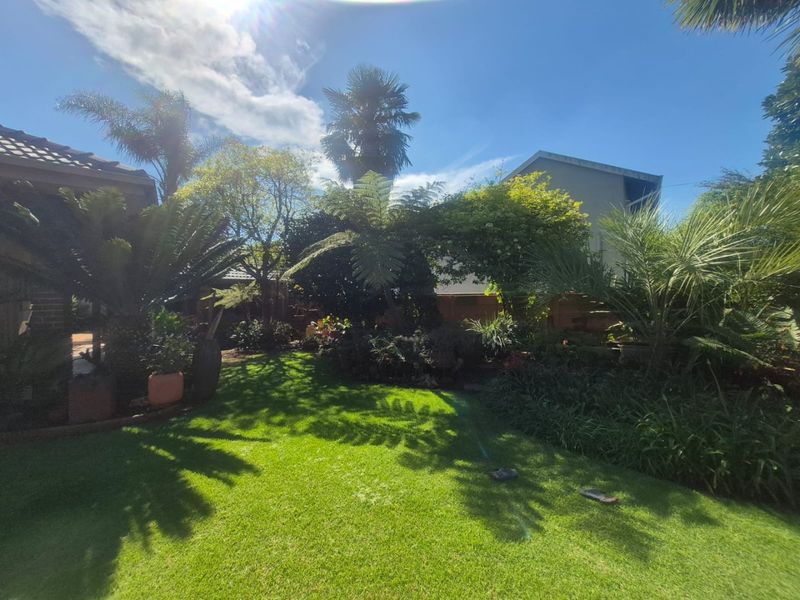 A well-maintained residential garden featuring a lush green lawn and mature trees, providing a private and tranquil outdoor space.