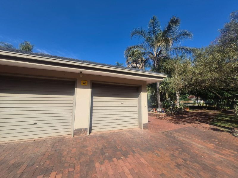 Exterior view of a double garage with brick paving and established garden surroundings.