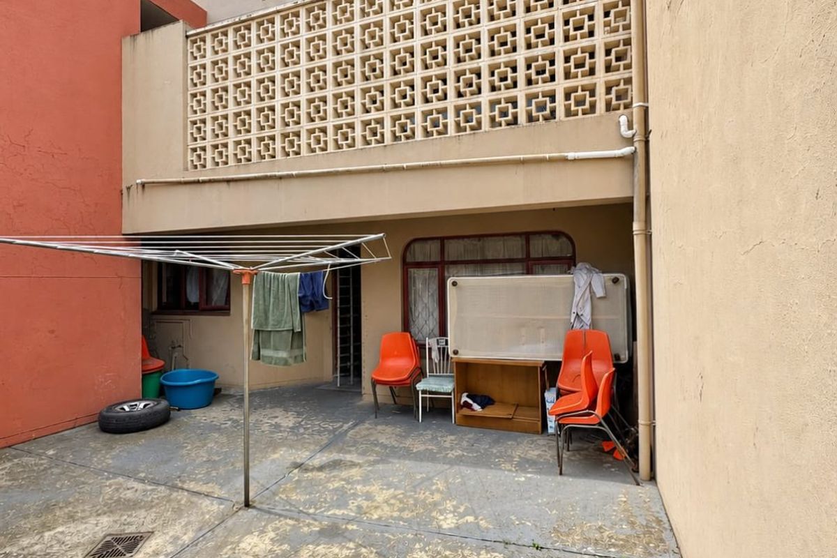 Rear exterior view of the property featuring a concrete patio area, decorative breeze block screen, and access to the main dwelling.