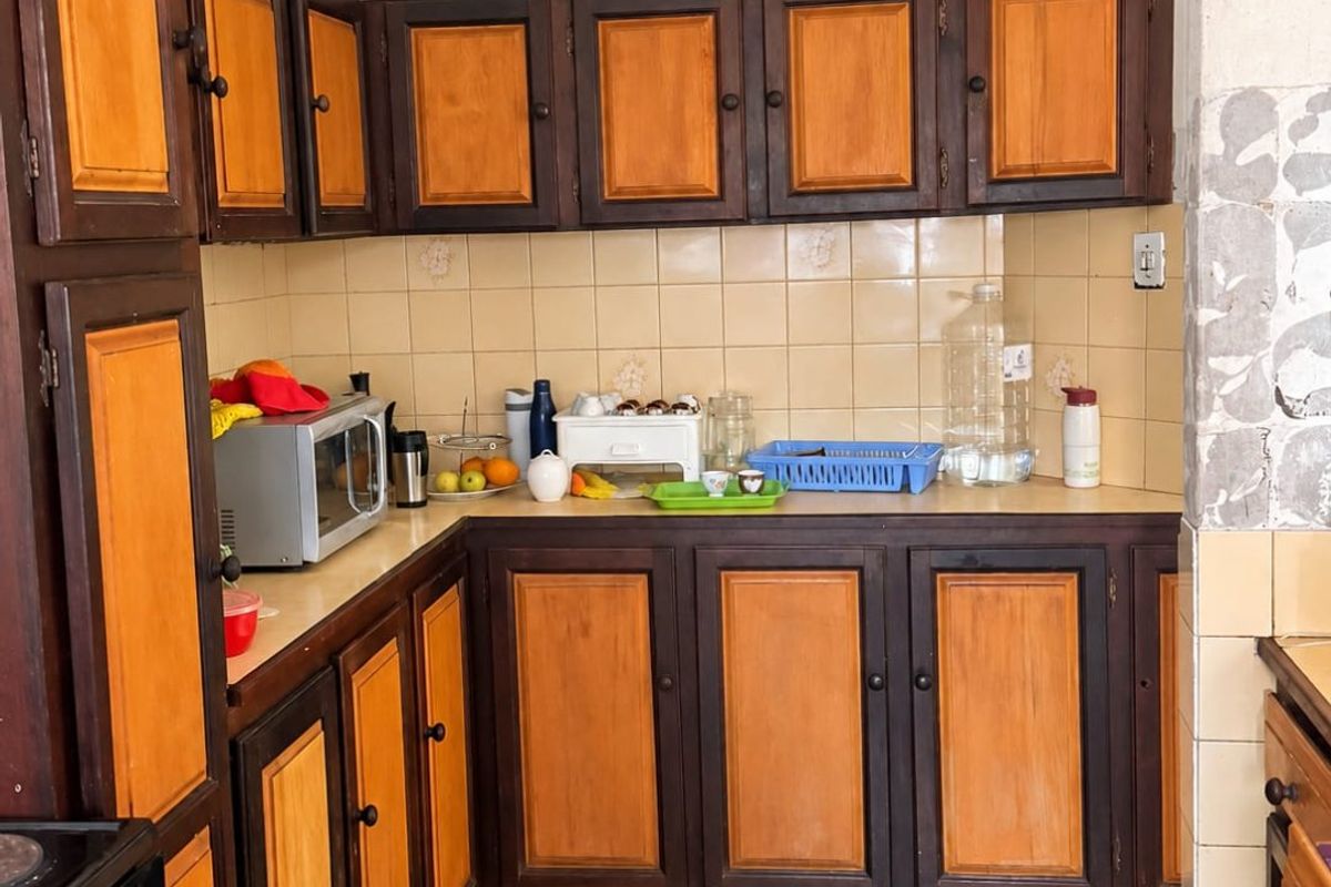 A dated kitchen featuring two-tone wooden cabinetry, ceramic tile backsplash, and vinyl flooring, offering significant potential for a modern renovation.
