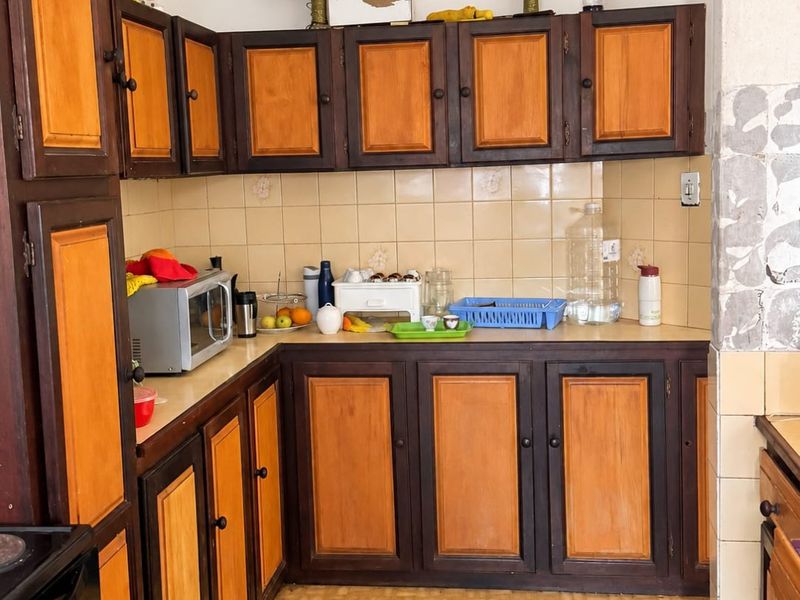 A dated kitchen featuring two-tone wooden cabinetry, ceramic tile backsplash, and vinyl flooring, offering significant potential for a modern renovation.