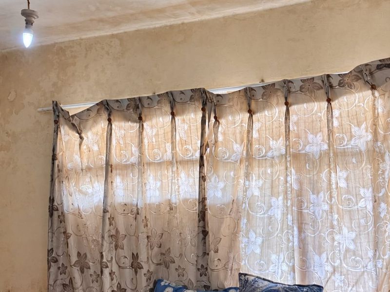 A bedroom interior showing significant signs of ceiling and wall deterioration, including visible staining and plaster damage, requiring maintenance and cosmetic repair.