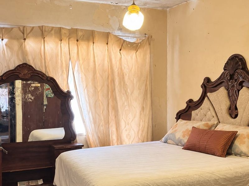 A bedroom featuring a pendant light fixture, currently requiring significant wall and ceiling repairs and cosmetic updates to improve the overall condition.
