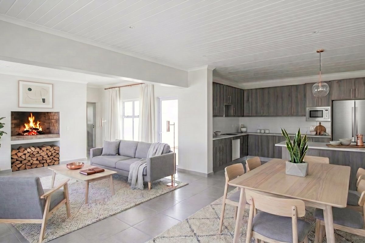 A modern open-plan living and kitchen area featuring a built-in fireplace, contemporary timber-look cabinetry, stone countertops, and high-quality tiled flooring throughout.