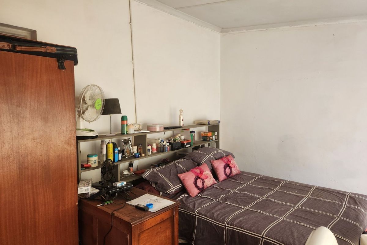 A bedroom featuring a built-in headboard shelving unit, requiring cosmetic updates to the walls and ceiling to improve the overall aesthetic.