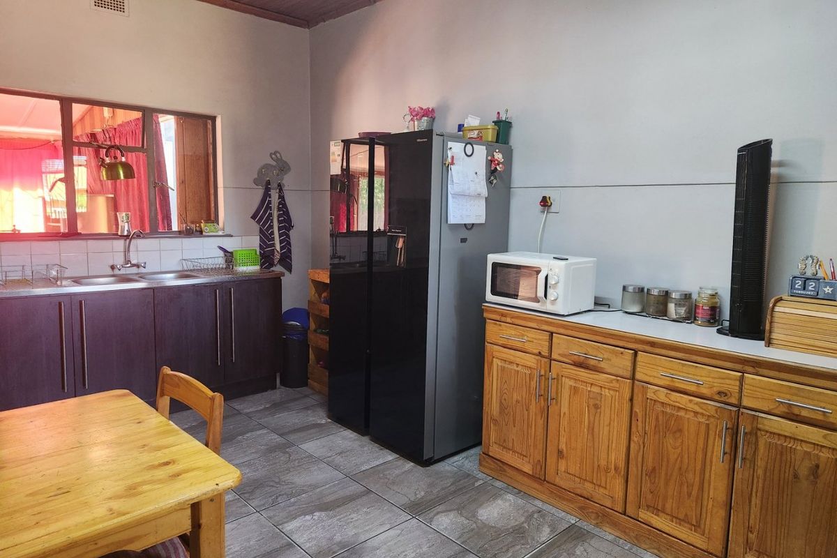 A functional kitchen featuring dark and timber cabinetry, tiled flooring, a double sink, and a tiled backsplash.