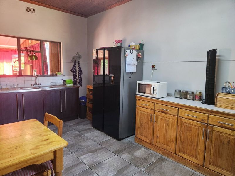 A functional kitchen featuring dark and timber cabinetry, tiled flooring, a double sink, and a tiled backsplash.