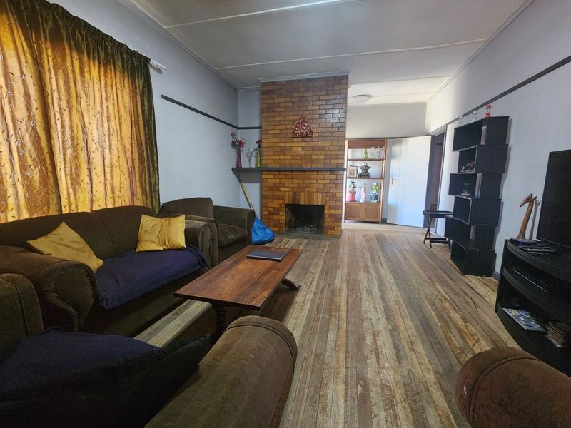 A living room featuring a central brick fireplace and original timber flooring, offering a classic foundation for renovation and modern updates.