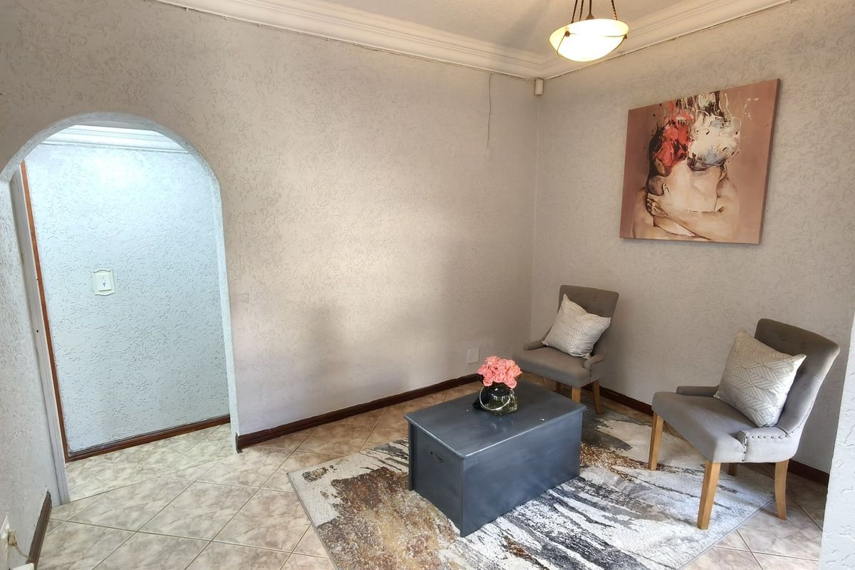 A living area featuring tiled flooring, an arched doorway, and coved ceiling cornices, offering a neutral base for potential interior design updates.
