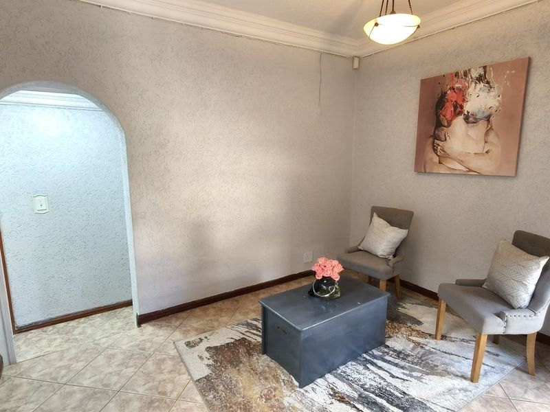 A living area featuring tiled flooring, an arched doorway, and coved ceiling cornices, offering a neutral base for potential interior design updates.