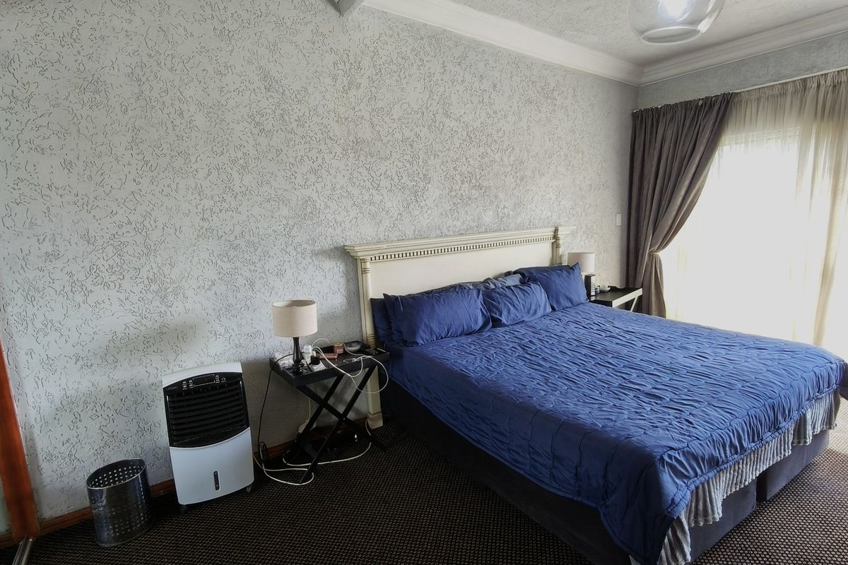 A spacious bedroom featuring a built-in headboard, textured wall finishes, and a sliding glass door providing access to an outdoor area.