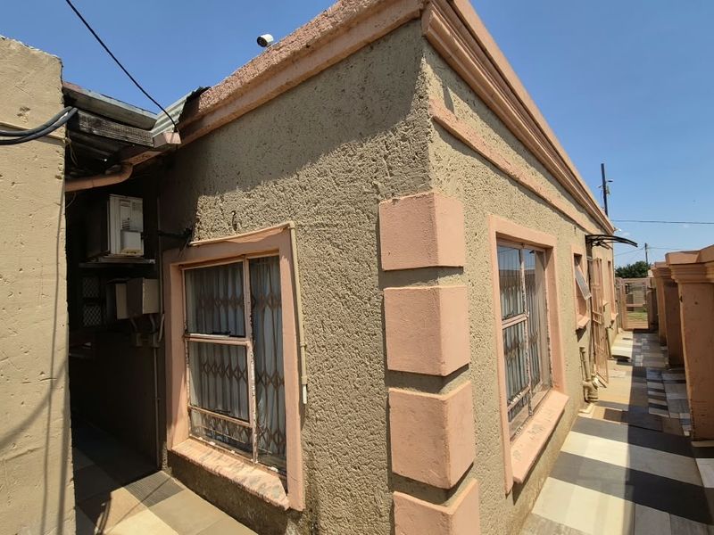 Exterior view of the property side passage featuring tiled flooring, security bars on windows, and perimeter walling.