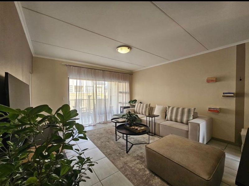 A comfortable living room featuring tiled flooring and a large sliding glass door that provides natural light and access to the balcony.