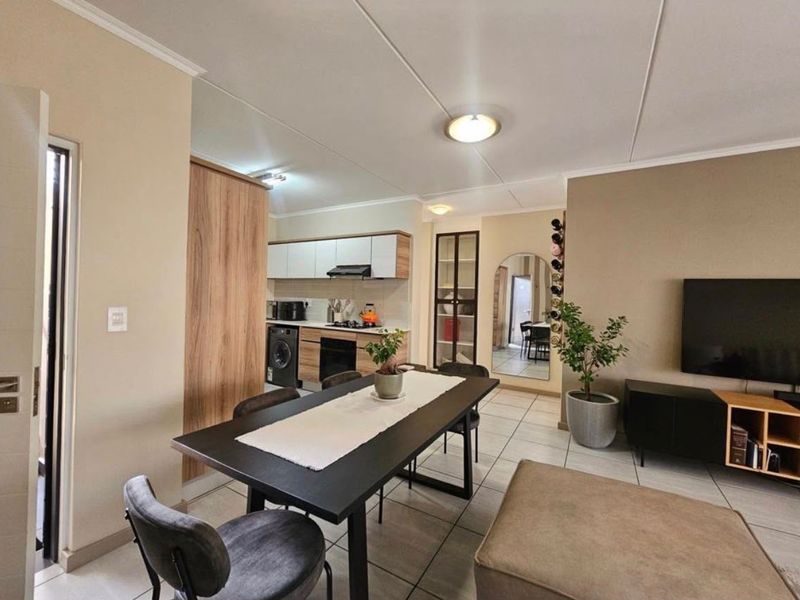 A well-maintained open-plan living and kitchen area featuring modern cabinetry, integrated appliances, and neutral tiled flooring throughout.