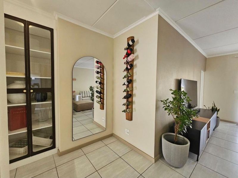 A well-maintained living area featuring tiled flooring, a built-in display cabinet, and coved ceiling details, creating a clean and functional space.