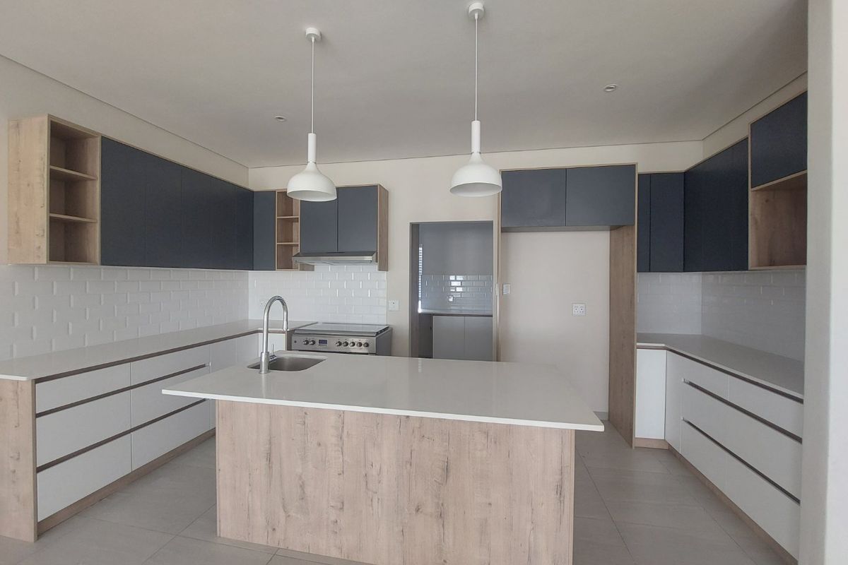Modern kitchen featuring a central island, quartz countertops, two-tone cabinetry, subway tile backsplash, and integrated stainless steel appliances.