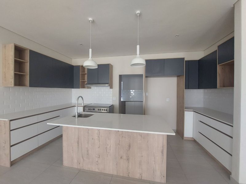 Modern kitchen featuring a central island, quartz countertops, two-tone cabinetry, subway tile backsplash, and integrated stainless steel appliances.