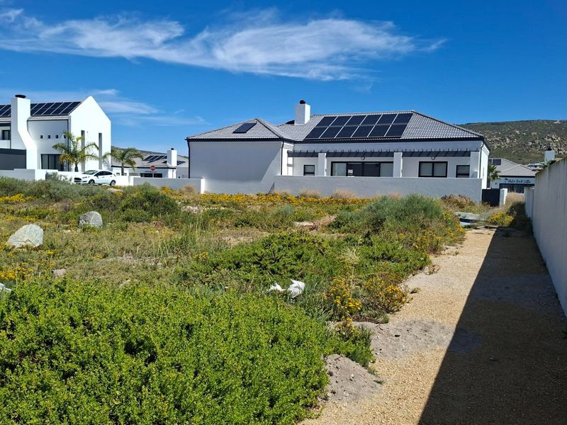 Rear view of a modern residential property featuring a tiled roof with integrated solar panels and a covered patio area.