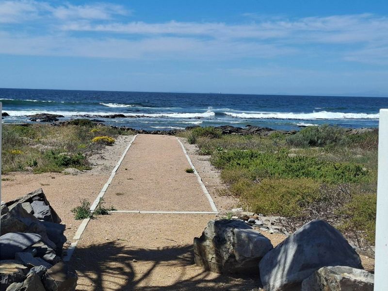 A scenic view of the ocean featuring a direct coastal access path framed by natural rock formations and coastal vegetation.