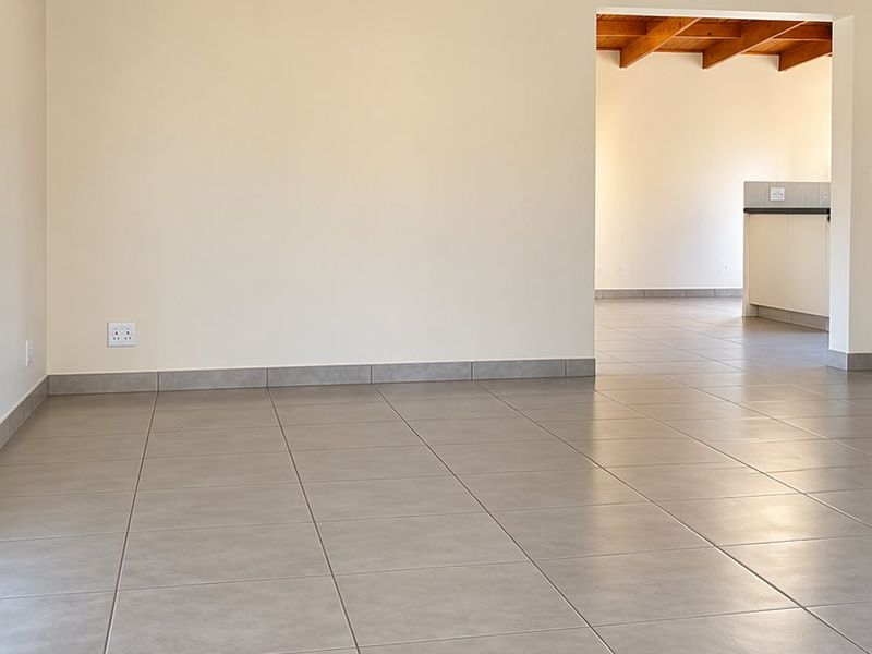 Spacious living area featuring high exposed timber beam ceilings and neutral tiled flooring, offering a bright and open layout.
