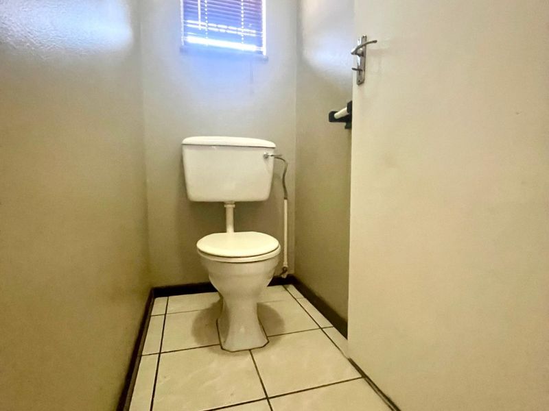 A compact, functional guest toilet featuring ceramic floor tiles and a small window for natural light and ventilation.