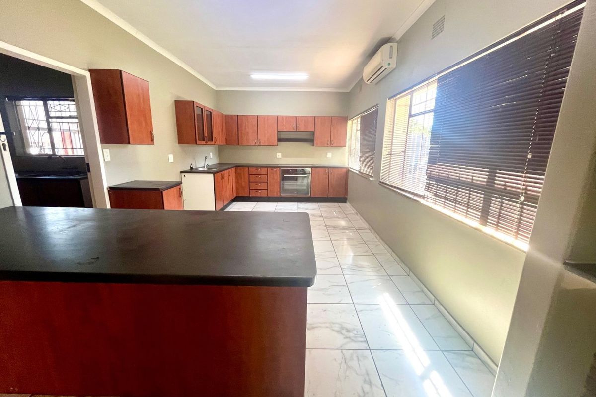 Spacious kitchen featuring built-in cabinetry, laminate countertops, integrated oven, extractor fan, and tiled flooring, offering a functional layout with ample natural light.