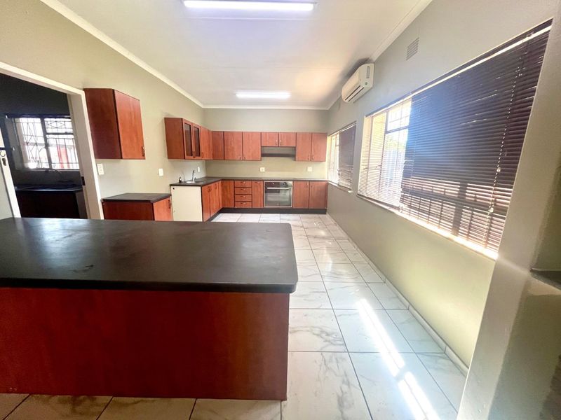 Spacious kitchen featuring built-in cabinetry, laminate countertops, integrated oven, extractor fan, and tiled flooring, offering a functional layout with ample natural light.