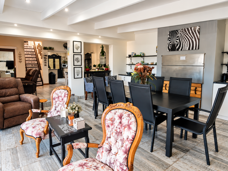 Spacious open-plan living and dining area featuring exposed ceiling beams, tiled flooring, and integrated cabinetry, creating a versatile and well-lit communal space.
