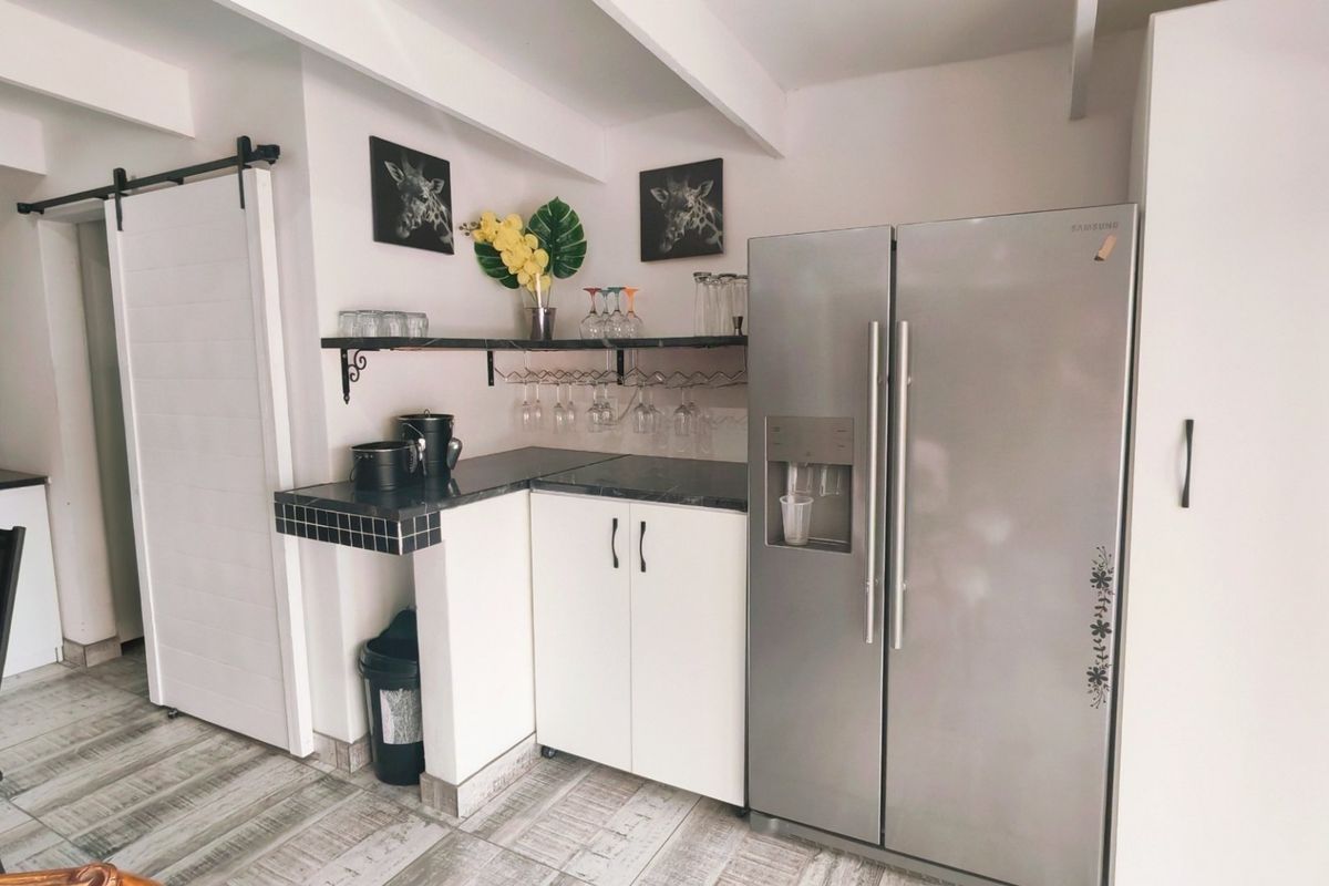 A functional kitchen area featuring tiled countertops, built-in cabinetry, a sliding barn door, and exposed ceiling beams, providing a practical and well-organized prep space.