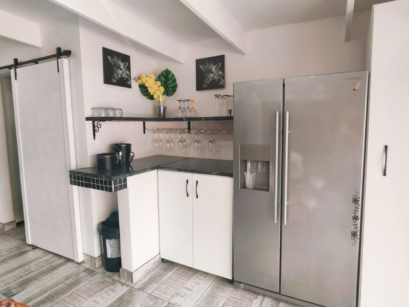 A functional kitchen area featuring tiled countertops, built-in cabinetry, a sliding barn door, and exposed ceiling beams, providing a practical and well-organized prep space.