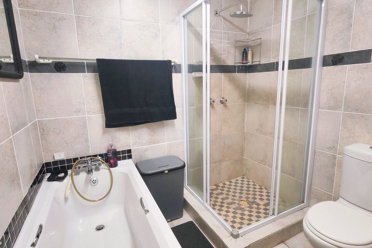 A functional bathroom featuring a built-in bathtub, a separate shower enclosure with tiled walls, and a standard toilet.