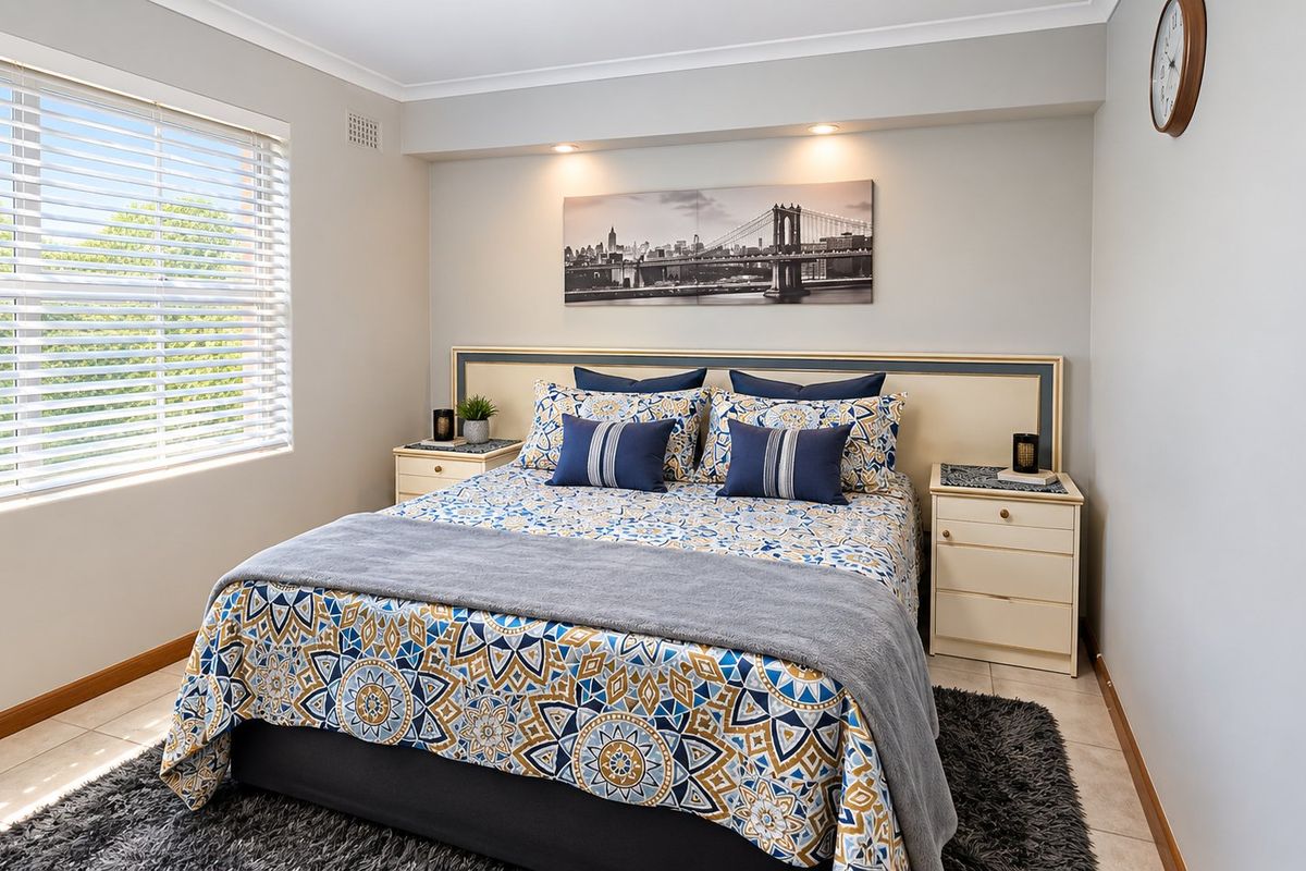 A well-maintained bedroom featuring tiled flooring, recessed downlighting, and large windows with venetian blinds, offering a bright and comfortable living space.