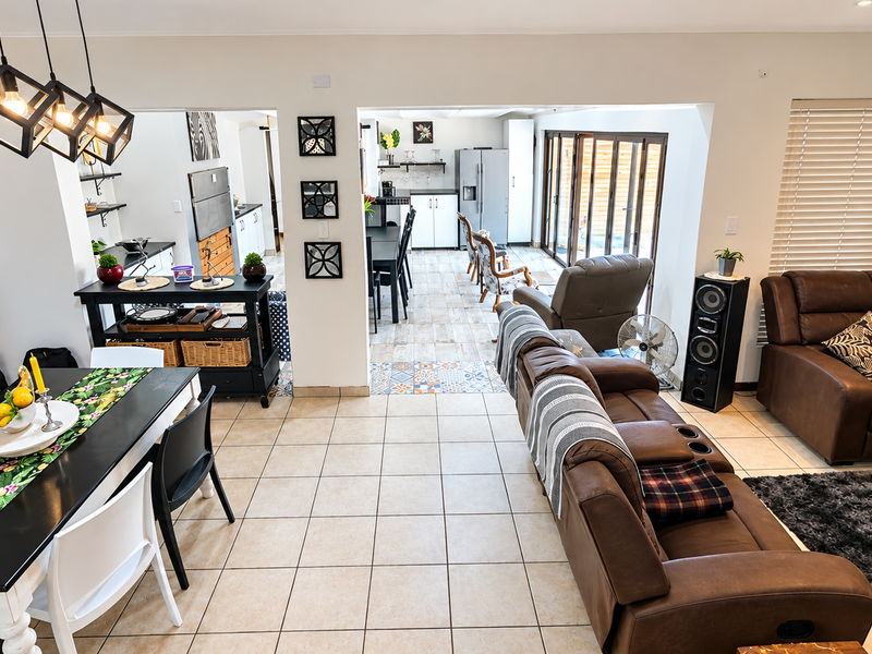 Spacious open-plan living and dining area featuring ceramic floor tiles, modern pendant lighting, and bi-fold doors leading to the outdoor space.