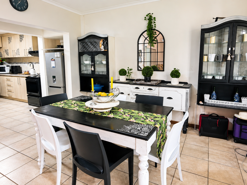 Open-plan dining area flowing into a functional kitchen with light wood cabinetry, granite countertops, and tiled flooring throughout.