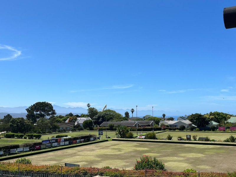 Elevated scenic view overlooking a landscaped lawn area with distant mountain and coastal vistas.