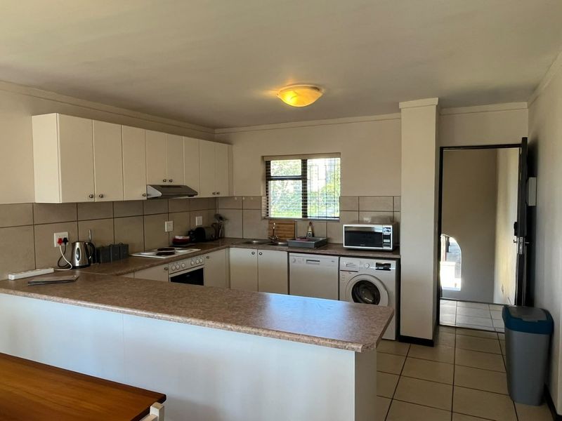 Functional kitchen featuring laminate countertops, built-in cabinetry, tiled backsplash, and integrated appliances, offering a practical layout with direct access to the hallway.