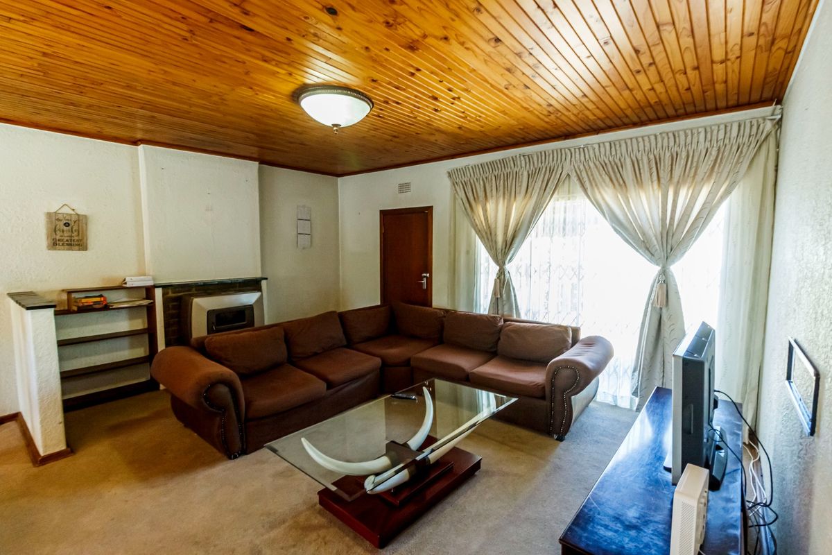 A living room featuring a wood-paneled ceiling, built-in fireplace, and built-in shelving, offering a cozy and traditional atmosphere.