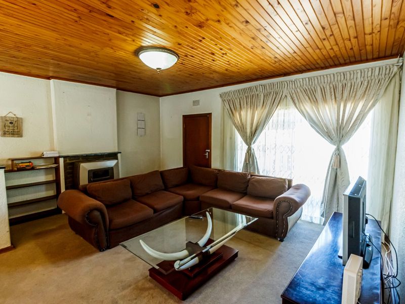 A living room featuring a wood-paneled ceiling, built-in fireplace, and built-in shelving, offering a cozy and traditional atmosphere.