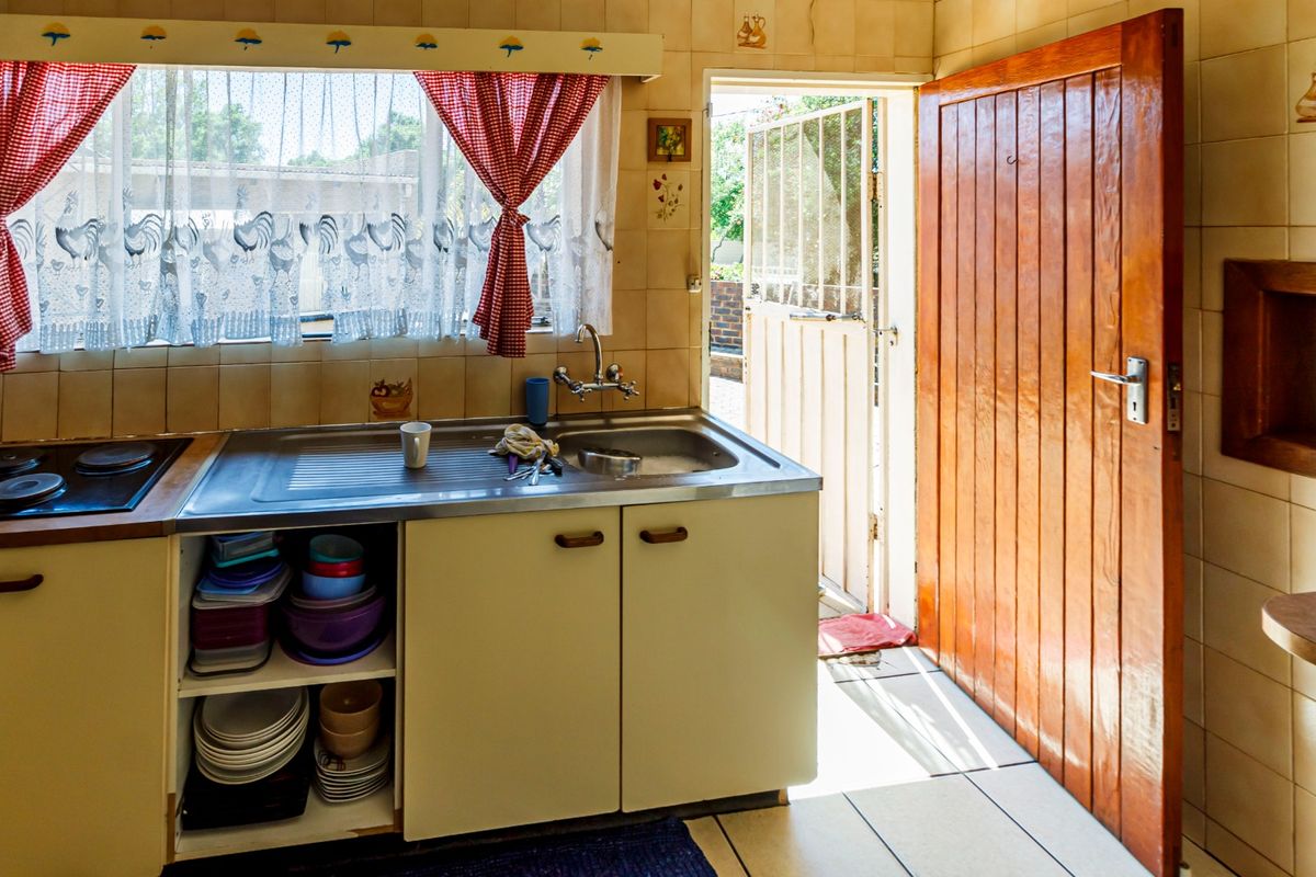 A functional kitchen featuring built-in cabinetry, a stainless steel sink, and direct access to the exterior through a timber door.