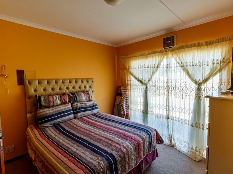 A bedroom featuring carpeted flooring, an integrated air conditioning unit, and a security gate over the window.