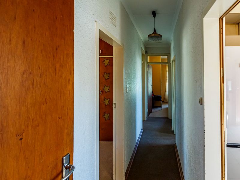 A functional hallway connecting multiple rooms, featuring textured walls, carpeted flooring, and built-in storage cupboards.