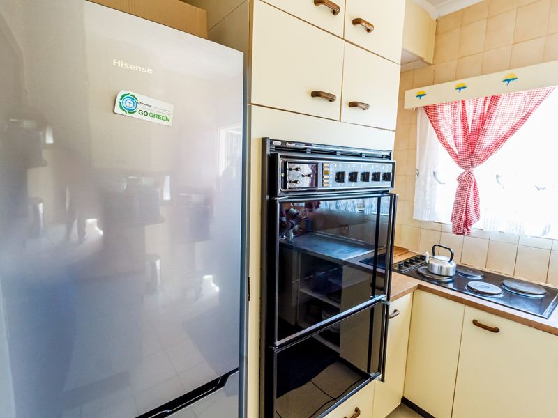 A compact kitchen featuring built-in cabinetry, an integrated oven, and an electric hob with tiled backsplash and laminate countertops.