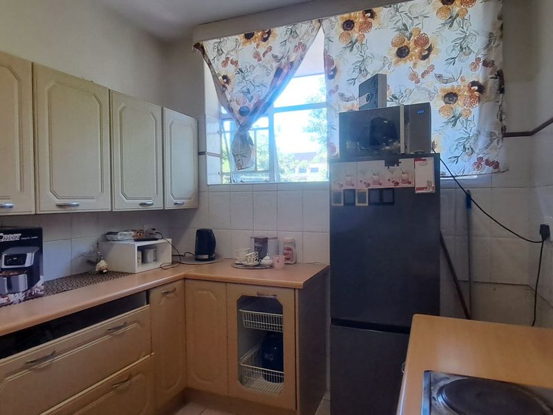 A functional kitchen featuring laminate countertops, built-in cabinetry, and ceramic wall tiling, offering a practical layout with an integrated electric hob.