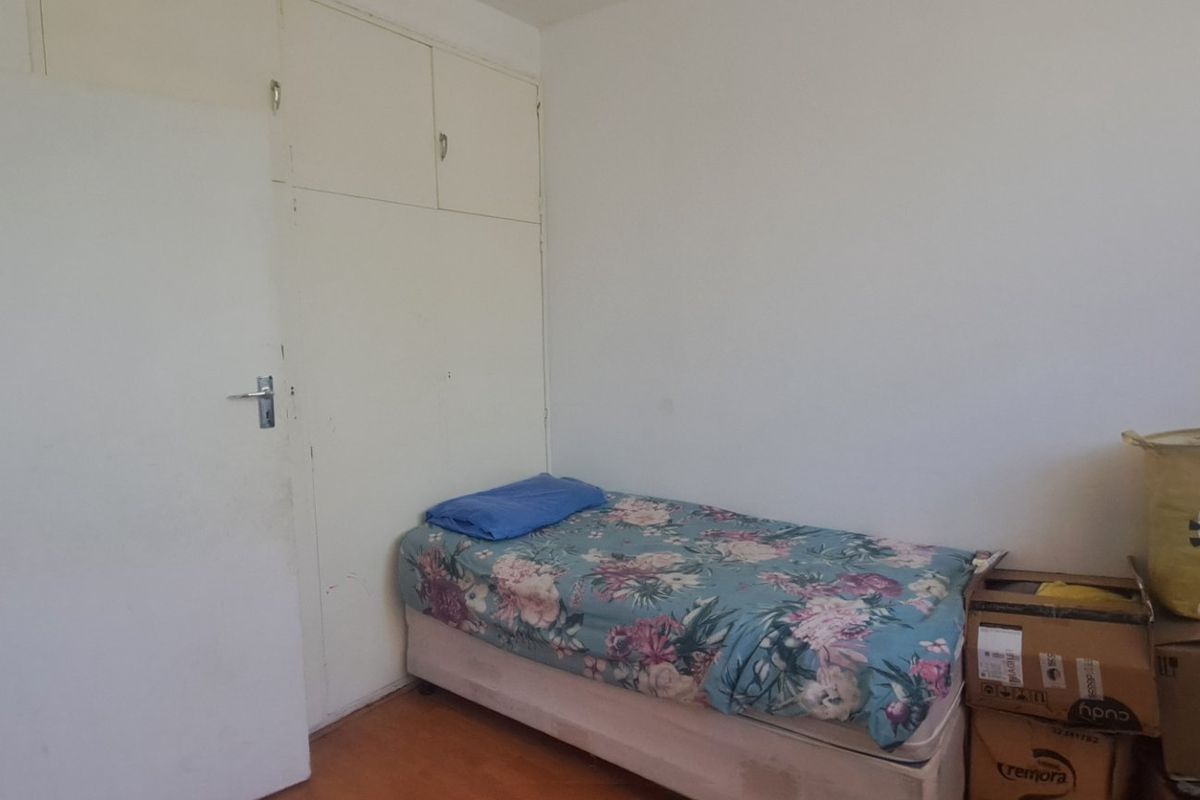 A bedroom featuring built-in cupboards and laminate flooring, requiring cosmetic updates to improve the overall aesthetic and condition of the space.