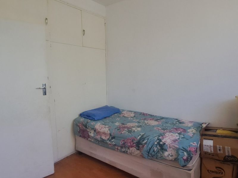 A bedroom featuring built-in cupboards and laminate flooring, requiring cosmetic updates to improve the overall aesthetic and condition of the space.