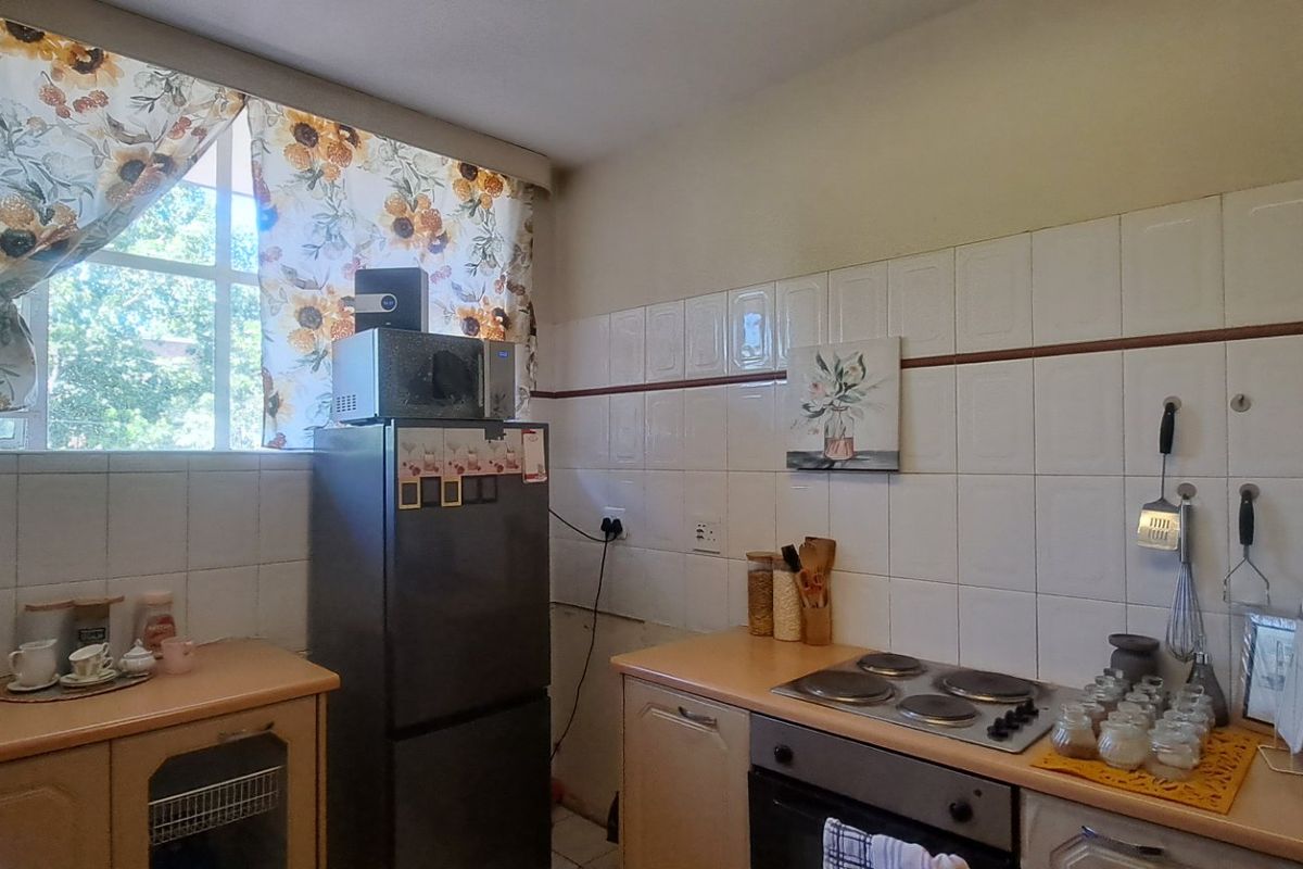 A functional kitchen featuring built-in cabinetry, laminate countertops, an electric hob, and an oven with tiled splashbacks.